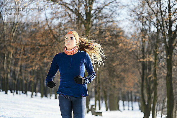 Junge Frau schaut im Winter beim Laufen weg