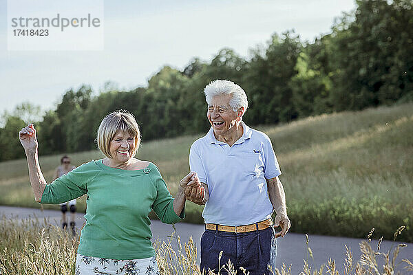 Fröhliches älteres Paar hält Händchen beim gemeinsamen Gehen