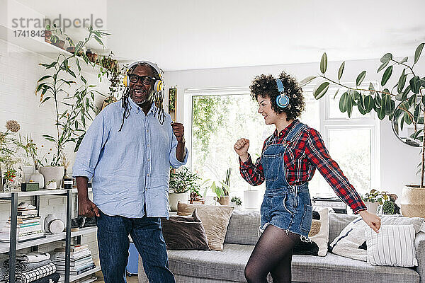 Verspielte Frau tanzt mit Vater im Wohnzimmer