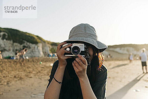 Junge Frau fotografiert mit der Kamera am Strand
