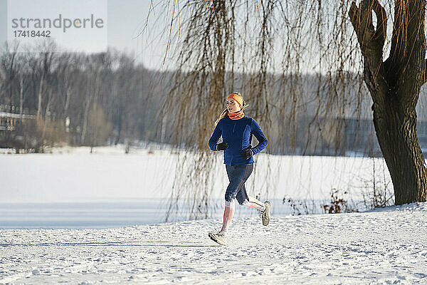 Frau läuft an sonnigem Tag auf Schnee
