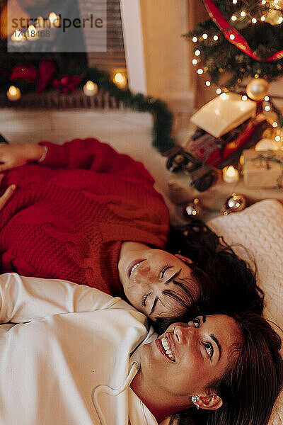 Lächelnde Freundinnen entspannen sich zu Weihnachten zu Hause