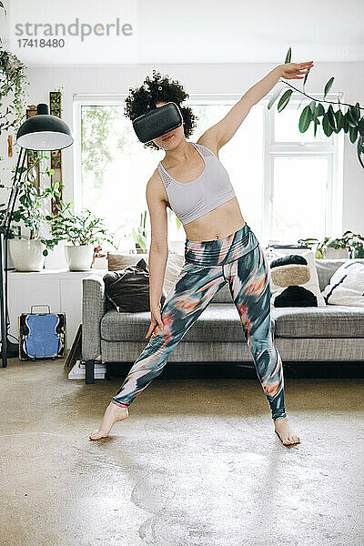 Frau nutzt Virtual-Reality-Headset beim Training im Wohnzimmer