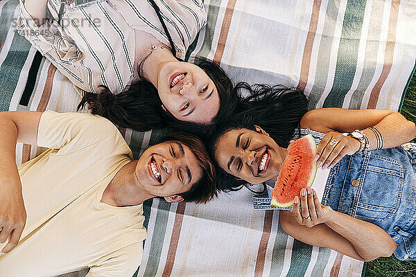 Happy friends lying together on picnic blanket
