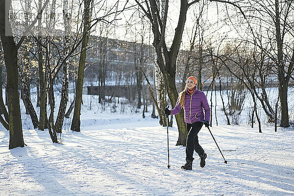 Frau mit Wanderstock läuft im Winter auf Schnee