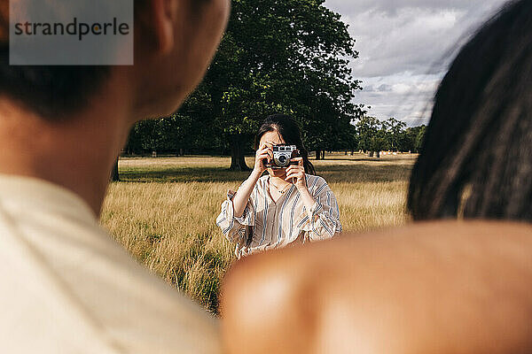 Frau fotografiert Freunde mit der Kamera im Park