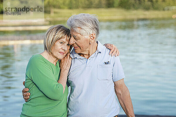 Ältere Frau stützte sich auf die Schulter eines Mannes am See