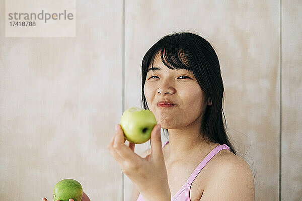 Junge Frau isst zu Hause Apfel