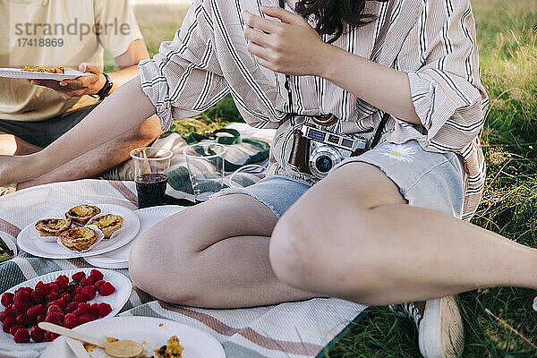 Freunde essen  während sie auf einer Picknickdecke sitzen