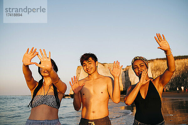 Männliche und weibliche Freunde gestikulieren am Strand