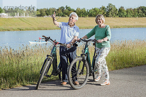 Älterer Mann zeigt  während er mit Frau spricht  die neben Fahrrädern steht