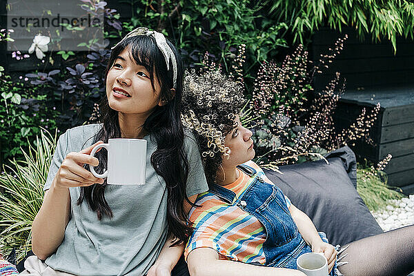 Junge Freunde entspannen sich mit Kaffeetassen auf einem Sitzsack im Hinterhof