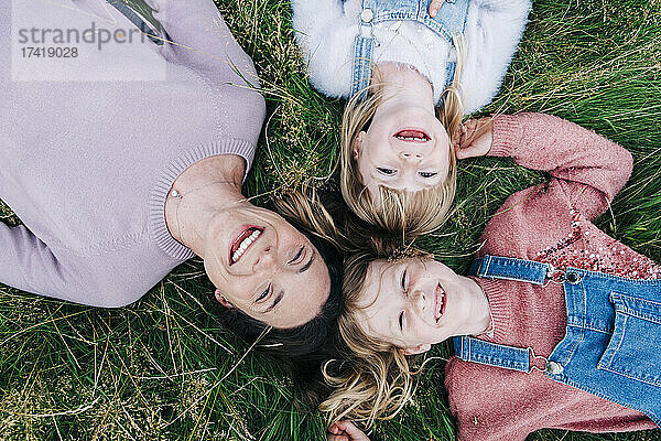 Lächelnde Mädchen liegen mit ihrer Mutter auf der Wiese