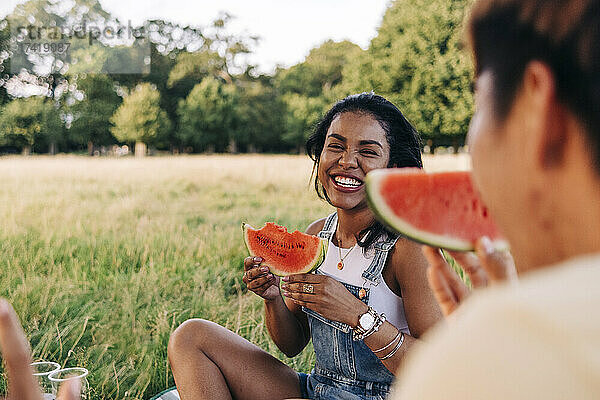 Lächelnde Freunde essen Wassermelone beim Picknick im Park