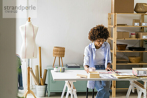 Weibliche Designprofi sitzt am Schreibtisch  während sie im Studio arbeitet