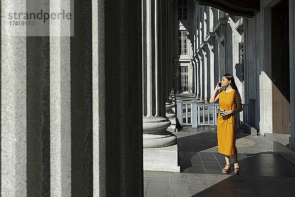 Frau spricht mit ihrem Smartphone  während sie in der Nähe der Säule der National Gallery in Singapur steht