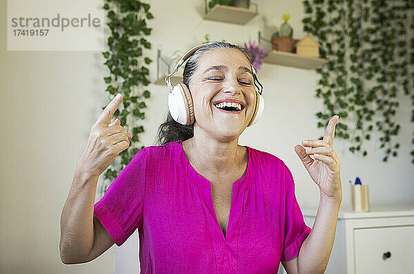 Fröhliche Frau  die Musik genießt  während sie zu Hause tanzt