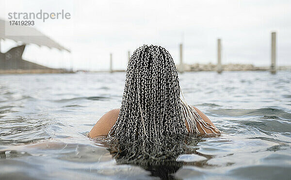 Junge Frau mit geflochtenen Haaren im Wasser am Wochenende