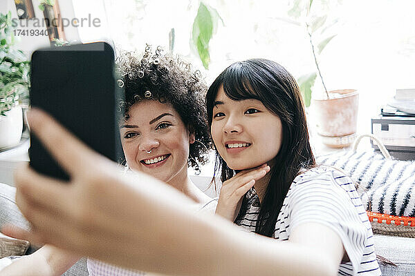 Lächelnde Freundinnen machen zu Hause ein Selfie mit dem Handy