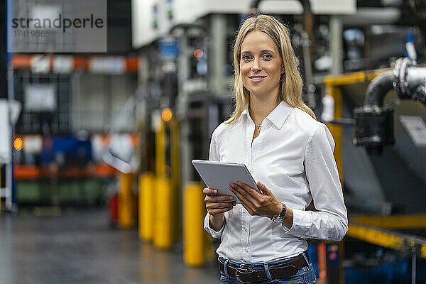 Berufstätige Frau mit digitalem Tablet steht in der Fabrik