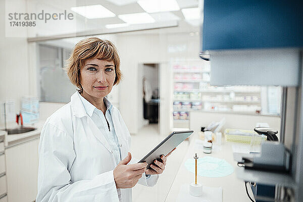 Weibliche Fachkraft hält digitales Tablet im Stehen im Labor