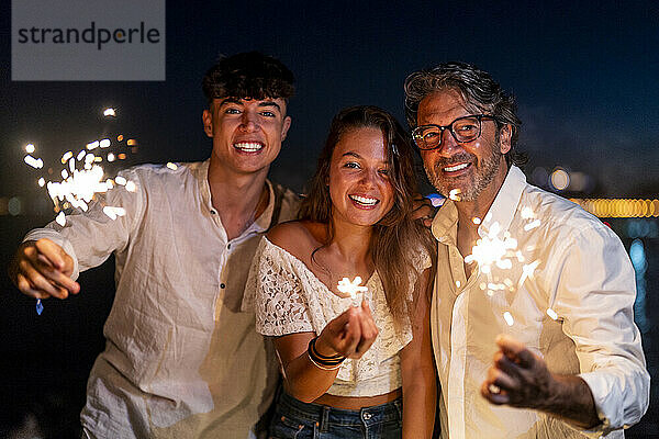 Familie genießt nachts Wunderkerzen am Strand