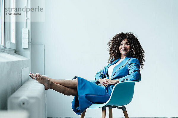 Lächelnde Geschäftsfrau  die auf einem Stuhl im Büro sitzt