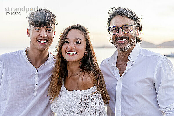 Schöne Frau steht mit Vater und Bruder am Strand