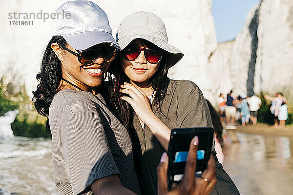 Glückliche Frau  die im Urlaub ein Selfie mit einer Freundin am Strand macht
