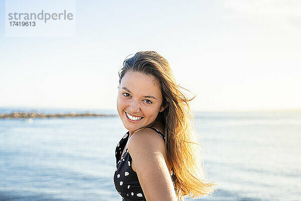 Schöne Frau mit braunen Haaren  die am Strand lächelt