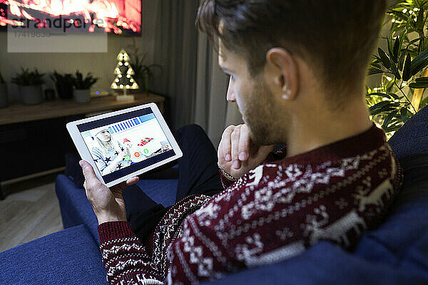 Junger Mann spricht zu Weihnachten mit Frau über digitales Tablet