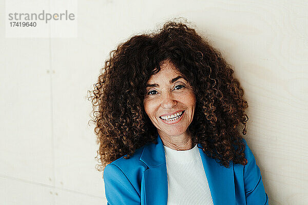 Geschäftsfrau mit lockigem Haar lächelt im Büro