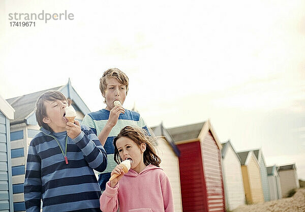 Mädchen und Jungen essen Eis am Strand