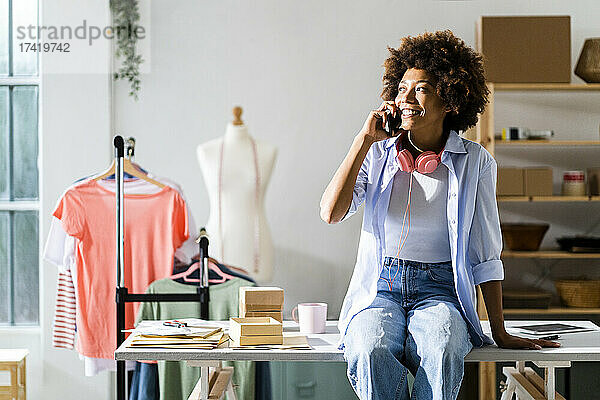 Geschäftsfrau spricht mit Smartphone  während sie im Studio am Schreibtisch sitzt