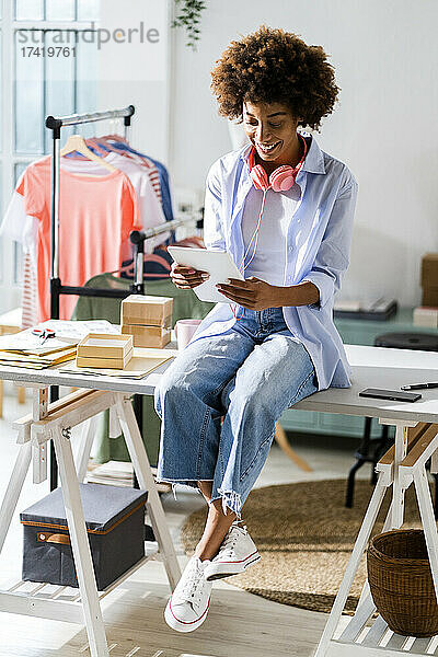 Modedesignerin nutzt digitales Tablet  während sie im Studio am Schreibtisch sitzt