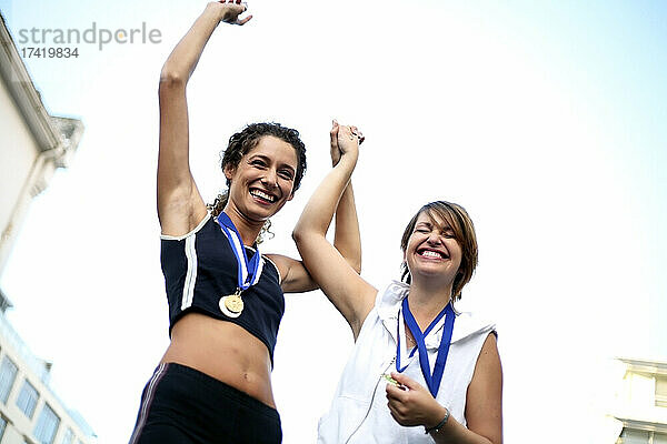 Glückliche Sportlerinnen tragen Medaillen und feiern Erfolge