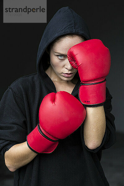 Entschlossene junge Sportlerin in roten Boxhandschuhen
