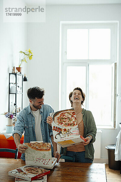 Glückliches Paar  das zu Hause Pizzakartons öffnet