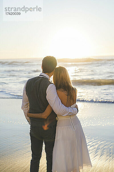 Frischvermähltes Paar mit Arm am Strand