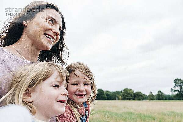 Mutter mit lächelnden Töchtern auf der Wiese