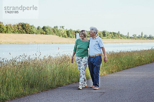 Lächelndes älteres Paar  das mit dem Arm um die Straße geht