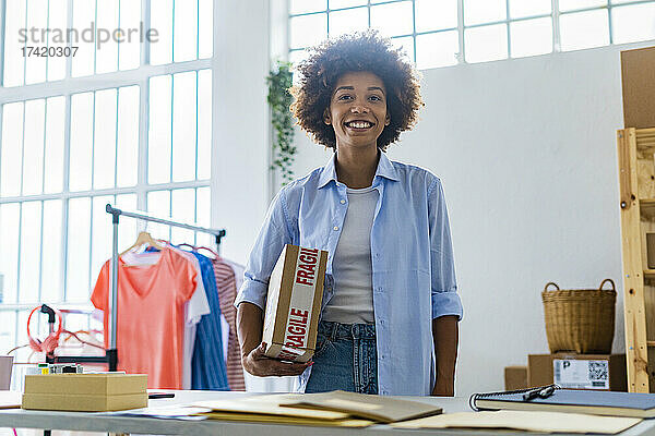 Lächelnde Unternehmerin steht  während sie das Paket im Studio hält