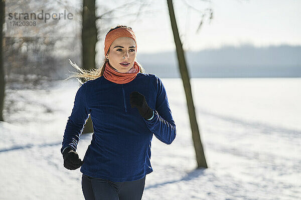 Junge Frau in Sportkleidung joggt im Winter