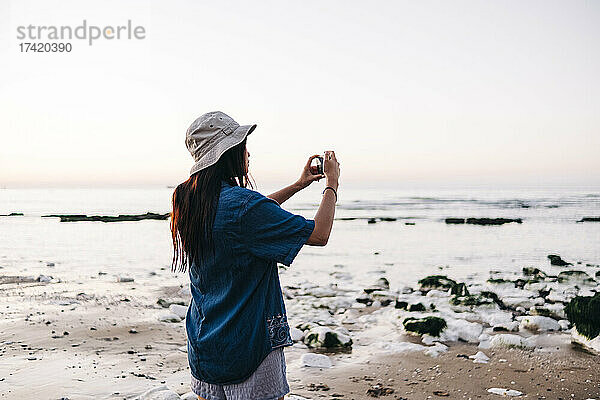 Frau mit Hut fotografiert im Urlaub am Strand