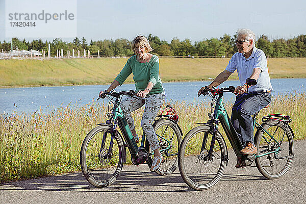 Paar fährt an sonnigen Tagen gemeinsam Fahrrad auf der Straße