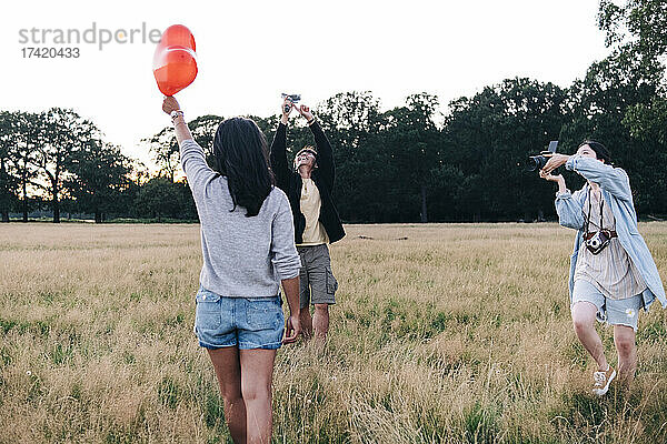 Freunde fotografieren mit Kamera und Mobiltelefon im Park