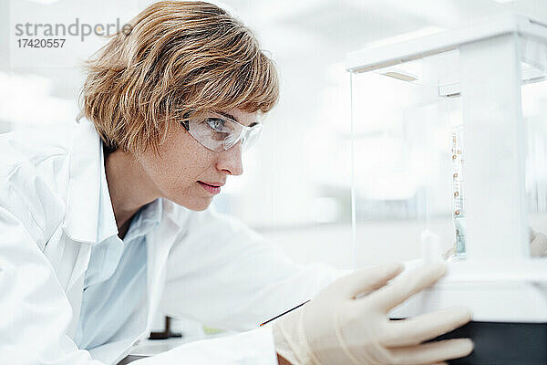 Weibliche Fachkraft mit Schutzbrillen-Prüfgeräten in der Apotheke