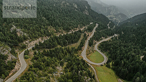 Drohnenaufnahme einer Landstraße  die sich durch ein bewaldetes Tal in den Pyrenäen erstreckt