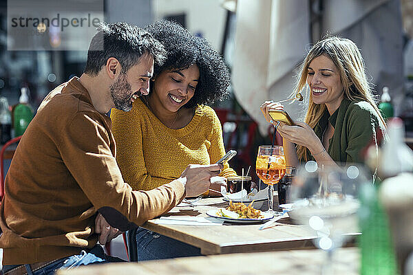 Männliche und weibliche Freunde nutzen Mobiltelefone im Restaurant