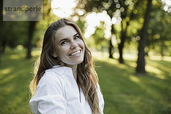 Schöne Frau mit braunen Haaren lächelt im Park